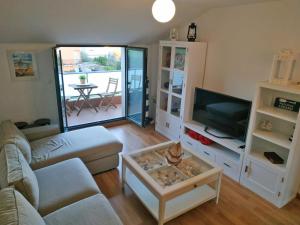 ein Wohnzimmer mit einem Sofa und einem TV in der Unterkunft O Faro, a 150 mtrs de playa Corna in San Pedro