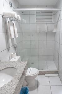 La salle de bains blanche est pourvue d'une douche et de toilettes. dans l'établissement Gran Lençóis Flat Residence 2 suítes com sala, à Barreirinhas