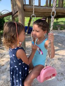 two little girls sitting on a swing at Pousada Ecológica Espelho D'Água in Carrancas