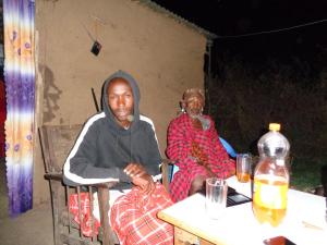 un homme et une femme assis à une table dans l'établissement Maasai homestay camping, à Sekenani