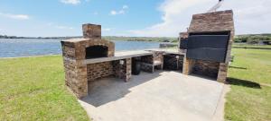 a stone barbecue with a table and a grill at Riverside Farm in eMalahleni