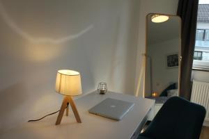 City Living near ICE/1&1/Fashion Outlet Montabaur في مونتابور: جهاز كمبيوتر محمول على طاولة مع مصباح عليه