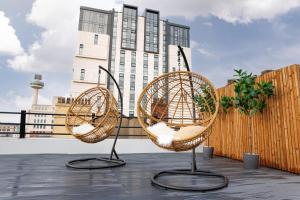 2 chaises en osier assises sur une terrasse avec un bâtiment dans l'établissement 44 Renshaw Apart Hotel, à Liverpool