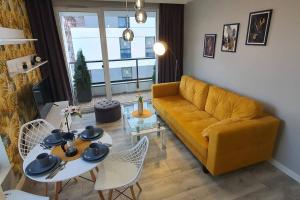 ein Wohnzimmer mit einem gelben Sofa und einem Tisch in der Unterkunft Apartament3City in Danzig