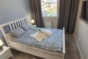a bedroom with a bed with a blue comforter and a window at Apartament3City in Gdańsk