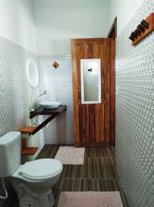 a bathroom with a toilet and a sink and a door at Pousada Quintal dos Sonhos Xandó Caraiva in Caraíva