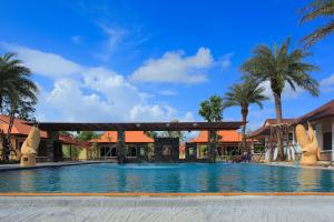 Pueanjai Resort and Restaurant في شومفون: مسبح في منتجع فيه نخل