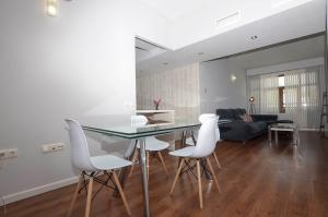 una cucina e un soggiorno con tavolo in vetro e sedie bianche di Apartamento completo - Centro de Algeciras a Algeciras