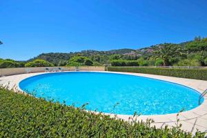 una gran piscina azul junto a un seto en Beautiful Villa 8 guests - Pool Access in Mandelieu, en Mandelieu-la-Napoule