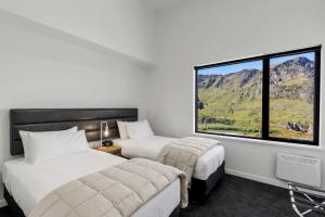 a hotel room with two beds and a large window at Riverview Penthouse - Apartment 19 in Queenstown