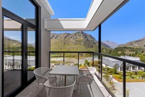 a room with a table and chairs on a balcony with mountains at Riverview Penthouse - Apartment 19 in Queenstown