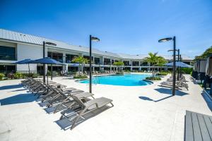 a swimming pool with lounge chairs and umbrellas at Anna Maria Beach Resort in Holmes Beach