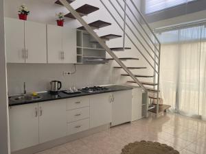 a kitchen with white cabinets and a spiral staircase at Amilcar Cabral Loft in Praia