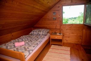 1 dormitorio en una cabaña de madera con cama y ventana en My dream house, en Vrhovci