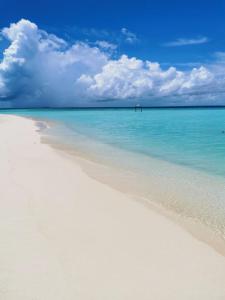 biała plaża z niebieską wodą i chmurami na niebie w obiekcie String Wave Maldives w mieście Gulhi