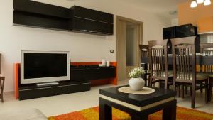 ein Wohnzimmer mit einem TV, einem Tisch und Stühlen in der Unterkunft Eka Luxury Two-Bedroom Penthouse in Durrës