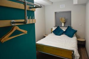 a small bedroom with a bed with blue pillows at Cwtsh Hostel Central Swansea, Social & Modern, Near Train Station in Swansea