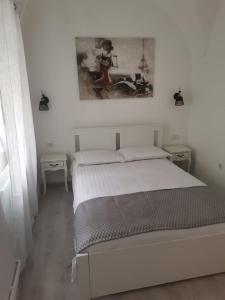 a white bedroom with a bed and a picture on the wall at Garsoniera Vivere in Sibiu