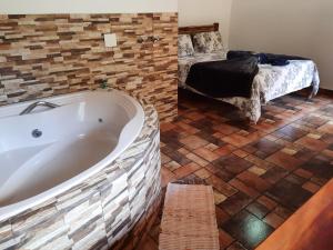 a bathroom with a bath tub and a bed at Pousada Bruxa Marela in Monte Verde +25 photos