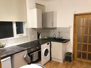 una cucina con armadietti bianchi e lavatrice di Modern Apartment in Twickenham Highstreet a Twickenham
