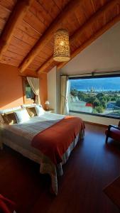 una camera da letto con un grande letto con una grande finestra di Hostería Encanto del Lolog a San Martín de los Andes