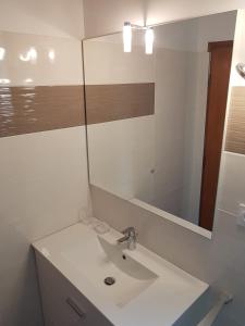 een witte badkamer met een wastafel en een spiegel bij DETENTE NATURE rando, ski , thermes in Allevard