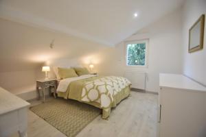 a white bedroom with a bed and a window at Campagne en ville! in Compiègne