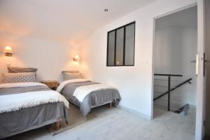 two beds in a room with white walls at Campagne en ville! in Compiègne
