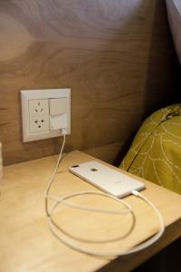 a laptop plugged into an electrical outlet next to a bed at Gente del Sur - Cinco Hermanos in Ushuaia