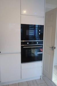 a kitchen with a microwave in a white kitchen at Spacious 4 bed Farnborough AirShow in Blackwater