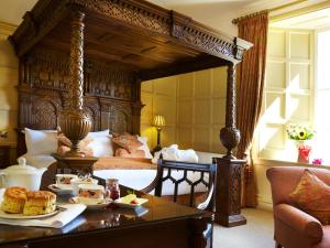 ein Schlafzimmer mit einem großen Himmelbett und einem Tisch mit Essen darauf in der Unterkunft The Wrea Head Hall Country House Hotel & Restaurant in Scarborough