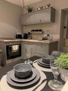 eine Küche mit einem Tisch mit Tellern und Gläsern darauf in der Unterkunft The Carriage House in Matlock