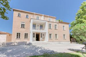 un grande edificio in mattoni con balcone sul lato anteriore di DOMAINE DE LA NERTHE- HOTEL PROVENCE MEDITERRANEE a Gignac-la-Nerthe