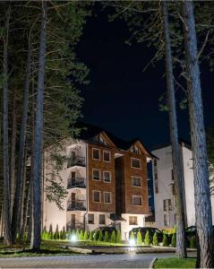a hotel at night with trees in the foreground at Apartman Pavle in Zlatibor