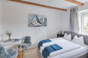 a white bedroom with a bed and a desk and a window at Innsbruck City Chalet in Innsbruck