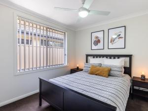 a bedroom with a bed and two windows at 15 Oasis Close Soldiers Point in Soldiers Point