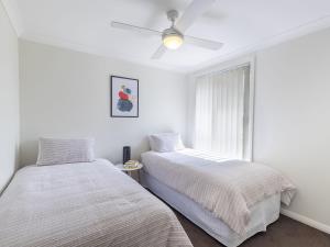 a bedroom with two beds and a window at 15 Oasis Close Soldiers Point in Soldiers Point