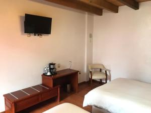 1 dormitorio con 1 cama y escritorio con TV en la pared en Hotel Malinalli en Huamantla