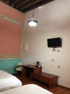 um quarto com uma secretária e uma televisão na parede em Hotel Malinalli em Huamantla