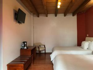 um quarto de hotel com duas camas e uma televisão em Hotel Malinalli em Huamantla