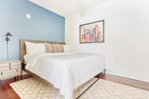 a bedroom with a white bed with a painting on the wall at Sonder The Irish House in New Orleans