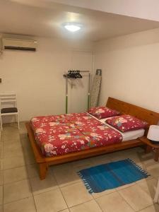 Schlafzimmer mit einem Bett mit roter Bettwäsche und einem Kühlschrank in der Unterkunft Location bas de maison in Sainte-Anne