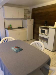 eine Küche mit einem Tisch und Stühlen sowie eine Küche mit einer Mikrowelle in der Unterkunft Location bas de maison in Sainte-Anne