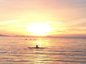 a person swimming in the ocean at sunset at Jasmine & Tea House in Mae Nam
