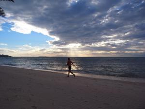 a man walking on the beach near the ocean at Jasmine & Tea House in Mae Nam
