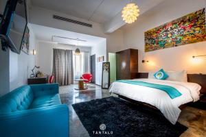 a bedroom with a large bed and a blue couch at Tantalo Hotel - Kitchen - Roofbar in Panama City