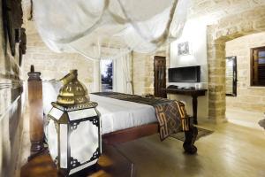 a bedroom with a bed with a lamp and a desk at The Charming Lonno Lodge Watamu in Watamu