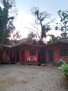 an orange house with white chairs in front of it at Chalés Bangalôs Itamambuca in Ubatuba