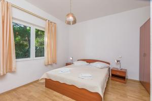 a white bedroom with a bed and a window at Apartment Ivan in Brela