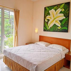 a bedroom with a bed with a painting on the wall at Hotel Flamboyan in Jember
